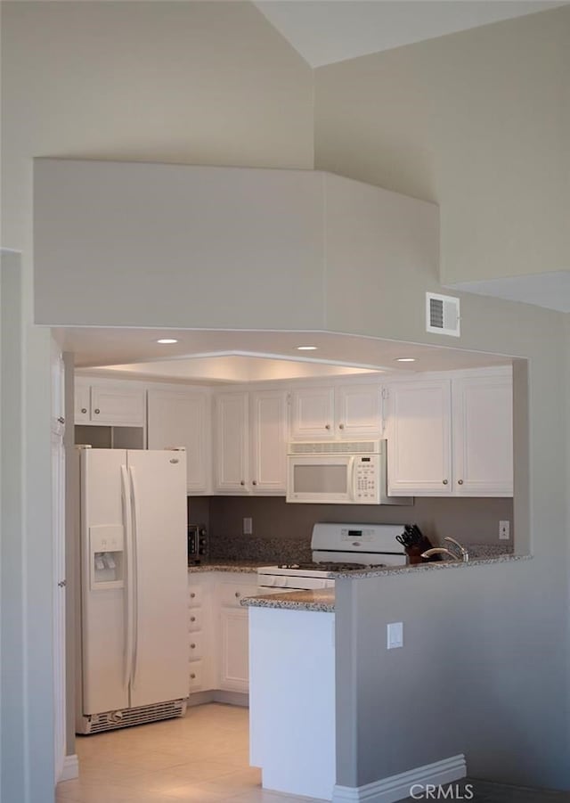 27971 Via Moreno, Laguna Niguel, CA 92677 - kitchen with white appliances, white cabinets, dark stone countertops, a peninsula, and light wood finished floors