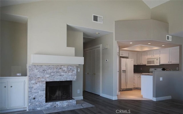 27971 Via Moreno, Laguna Niguel, CA 92677 - kitchen with white appliances, wood finished floors, white cabinetry, a fireplace, and a towering ceiling