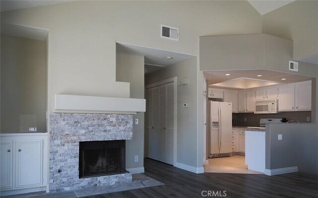 27971 Via Moreno, Laguna Niguel, CA 92677 - kitchen with white appliances, wood finished floors, white cabinetry, a fireplace, and a towering ceiling