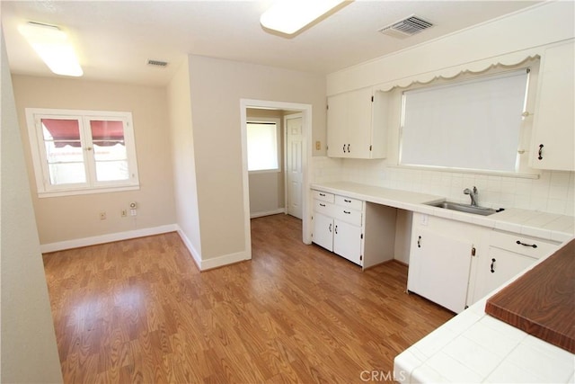 3641 Adams St, Riverside, CA 92504 - kitchen featuring a sink, tile countertops, light wood-style flooring, white cabinetry, and backsplash