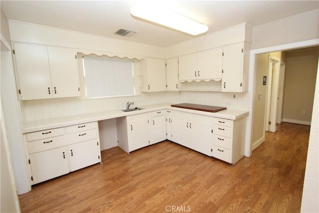 3641 Adams St, Riverside, CA 92504 - kitchen featuring decorative backsplash, white cabinetry, light wood-style flooring, light countertops, and a sink