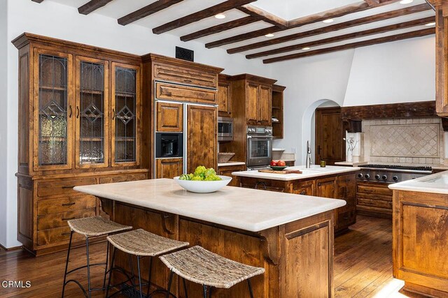 4144 Chevy Chase Dr, La Canada Flintridge, CA 91011 - kitchen featuring a kitchen island, arched walkways, built in appliances, beam ceiling, and decorative backsplash