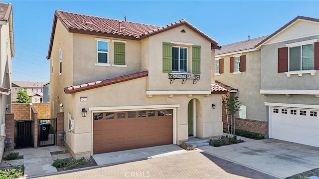 16233 Lozano St Unit 2, Fontana, CA 92336 - mediterranean / spanish-style home featuring an attached garage, a tile roof, stucco siding, decorative driveway, and a gate