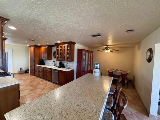 27568 Linda Vista Rd, Barstow, CA 92311 - kitchen with stainless steel dishwasher, a sink, light countertops, a ceiling fan, and glass insert cabinets