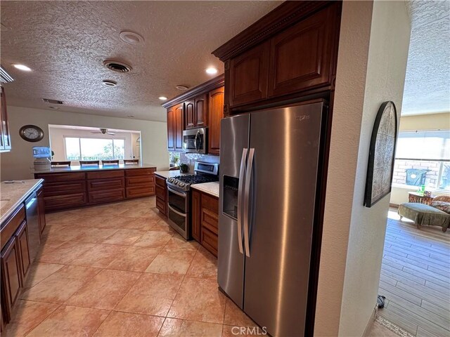 27568 Linda Vista Rd, Barstow, CA 92311 - kitchen with appliances with stainless steel finishes, a textured ceiling, recessed lighting, and light countertops