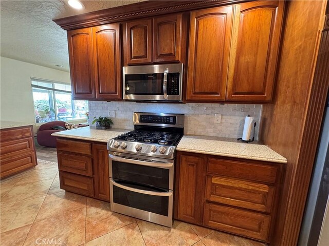 27568 Linda Vista Rd, Barstow, CA 92311 - kitchen with appliances with stainless steel finishes, backsplash, a textured ceiling, light tile patterned flooring, and light stone counters