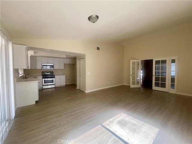 1305 Herzel Ave, Lancaster, CA 93535 - unfurnished living room with wood finished floors, baseboards, french doors, a sink, and plenty of natural light