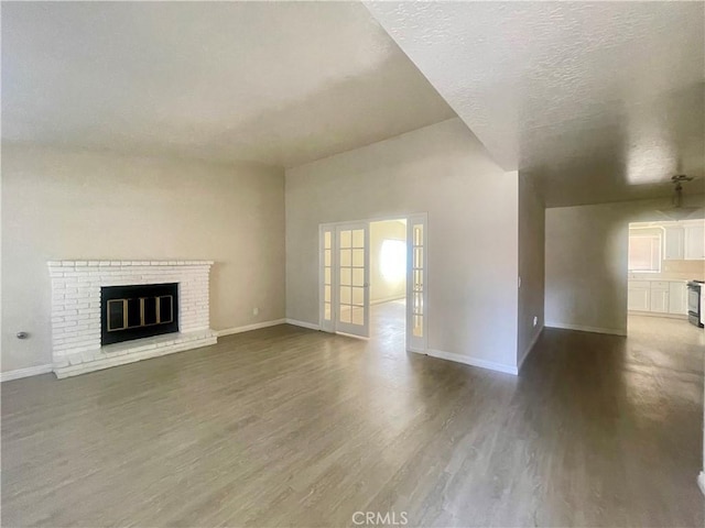 1305 Herzel Ave, Lancaster, CA 93535 - unfurnished living room featuring dark wood-style floors, baseboards, a brick fireplace, and french doors