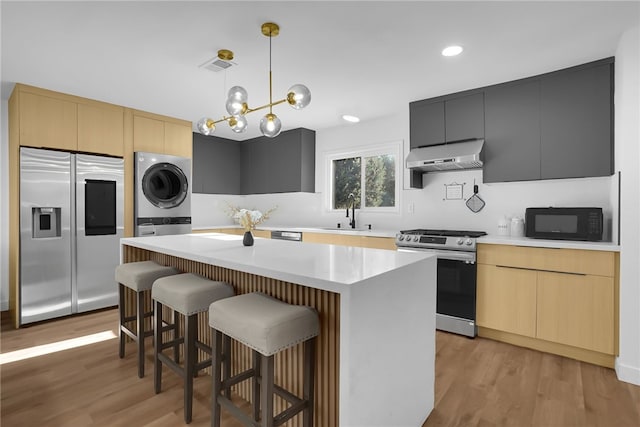 5548 Irondale Ave, Los Angeles, CA 91367 - kitchen with stainless steel appliances, estacked washer and dryer, under cabinet range hood, light wood-style floors, and a center island