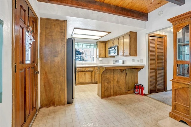 33079 Ridge Rd, Arrowbear, CA 92382 - kitchen with stainless steel appliances, a peninsula, light countertops, brown cabinets, and wooden ceiling with exposed beams