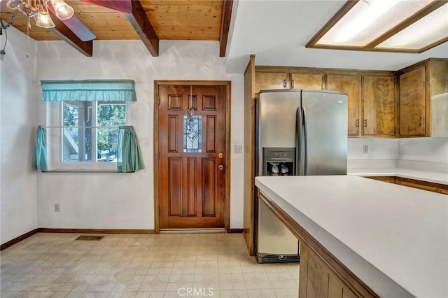 33079 Ridge Rd, Arrowbear, CA 92382 - kitchen with stainless steel fridge with ice dispenser, brown cabinetry, light flooring, wooden ceiling with exposed beams, and light countertops