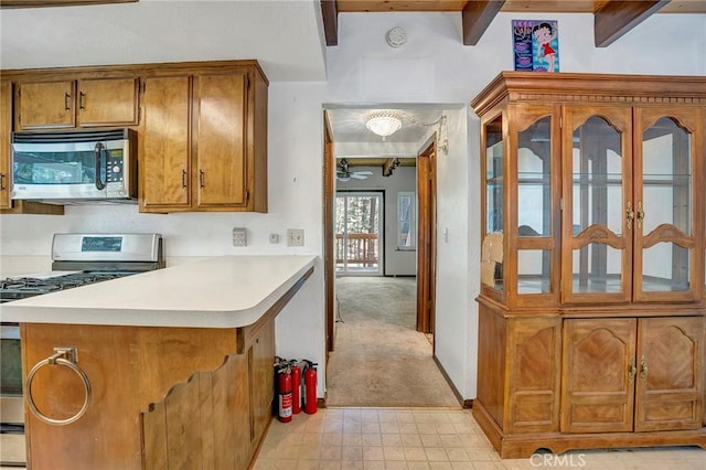 33079 Ridge Rd, Arrowbear, CA 92382 - kitchen with stainless steel appliances, brown cabinets, light countertops, a peninsula, and beamed ceiling