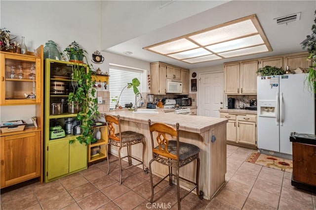 44044 11th St E, Lancaster, CA 93535 - kitchen with white appliances, a breakfast bar, tile countertops, a peninsula, and light tile patterned floors