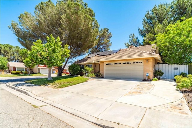 44044 11th St E, Lancaster, CA 93535 - view of front facade with a tile roof, a garage, solar panels, stucco siding, and driveway