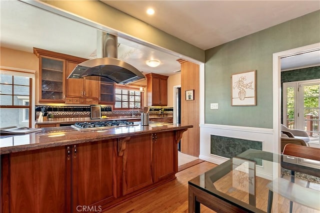 2042 E Crary St, Pasadena, CA 91104 - kitchen with island range hood, stainless steel gas stovetop, light wood finished floors, brown cabinets, and dark stone counters