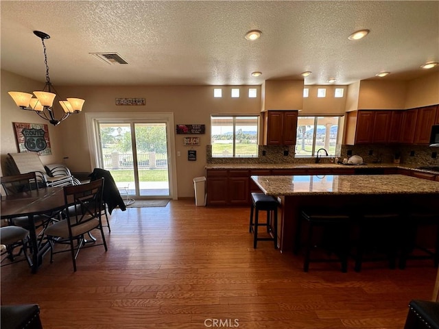 915 Beach Dr, Needles, CA 92363 - kitchen with a chandelier, a textured ceiling, light wood-style flooring, a kitchen bar, and backsplash