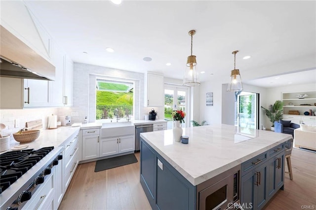 32 Bargemon, Newport Coast, CA 92657 - kitchen featuring appliances with stainless steel finishes, white cabinets, custom exhaust hood, a center island, and light wood-type flooring