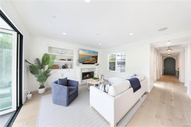 32 Bargemon, Newport Coast, CA 92657 - living area featuring light wood-style flooring, a high end fireplace, built in features, recessed lighting, and baseboards