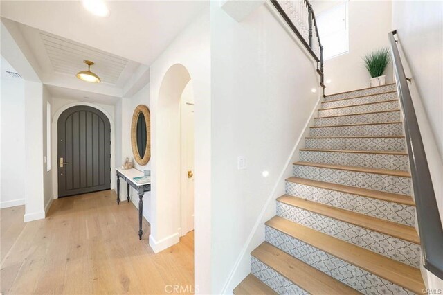 32 Bargemon, Newport Coast, CA 92657 - foyer featuring arched walkways, light wood-style flooring, baseboards, stairway, and a raised ceiling