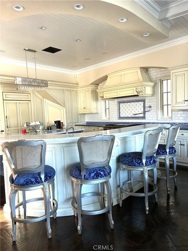 59 Rivo Alto Canal, Long Beach, CA 90803 - kitchen featuring premium range hood, cream cabinetry, crown molding, backsplash, and a breakfast bar