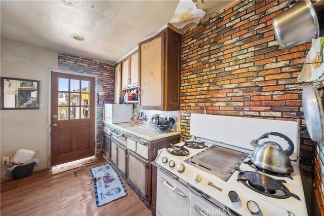 20717 Raymond Ave, Torrance, CA 90502 - kitchen with white gas range, light wood finished floors, brick wall, and light countertops