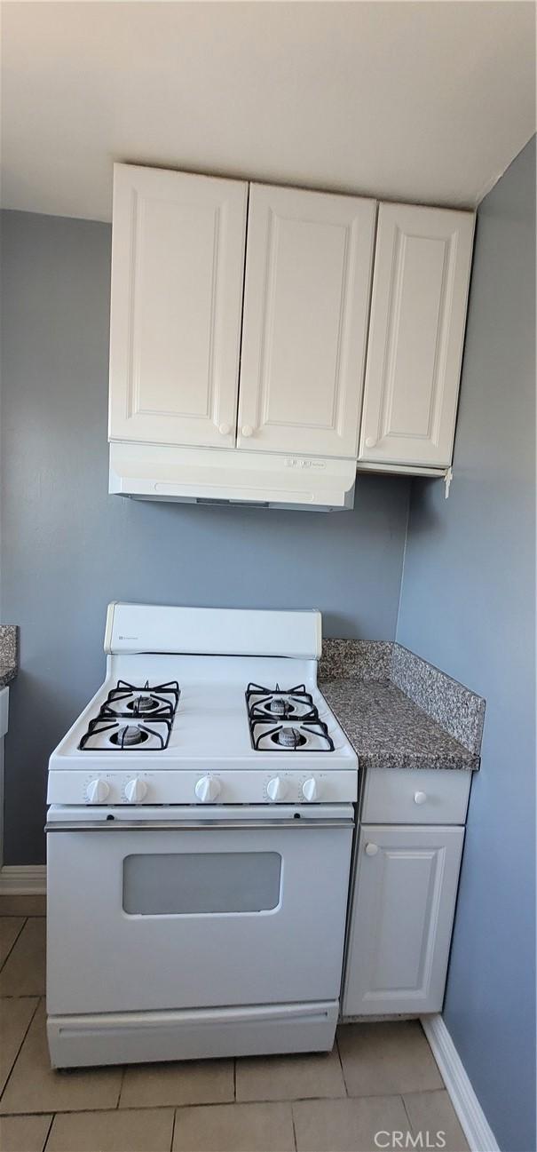 7107 Coldwater Canyon Ave, North Hollywood, CA 91605 - kitchen featuring white gas range, light tile patterned floors, baseboards, and white cabinets