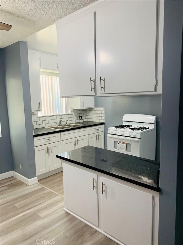 7107 Coldwater Canyon Ave, North Hollywood, CA 91605 - kitchen with white gas stove, a sink, light wood-style floors, decorative backsplash, and white cabinets