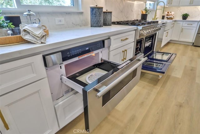 13181 Olympia Way N, Tustin, CA 92705 - kitchen featuring tasteful backsplash, white cabinetry, light wood-style floors, and light stone counters