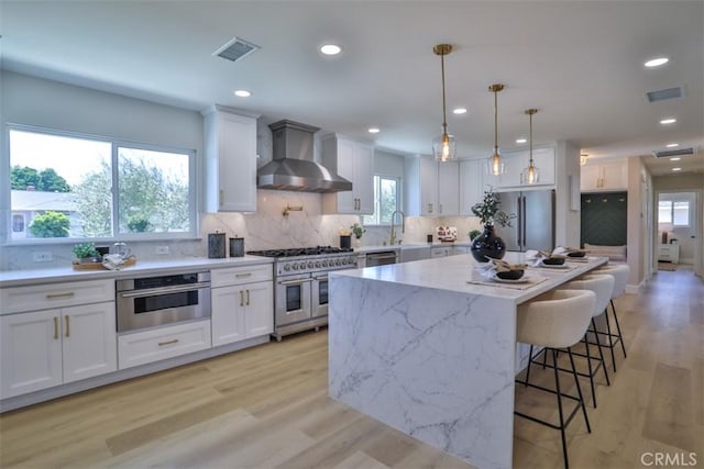 13181 Olympia Way N, Tustin, CA 92705 - kitchen featuring wall chimney exhaust hood, stainless steel appliances, white cabinetry, backsplash, and recessed lighting