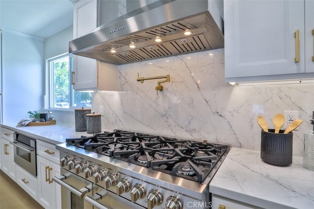 13181 Olympia Way N, Tustin, CA 92705 - kitchen featuring appliances with stainless steel finishes, wall chimney range hood, white cabinetry, backsplash, and light stone countertops