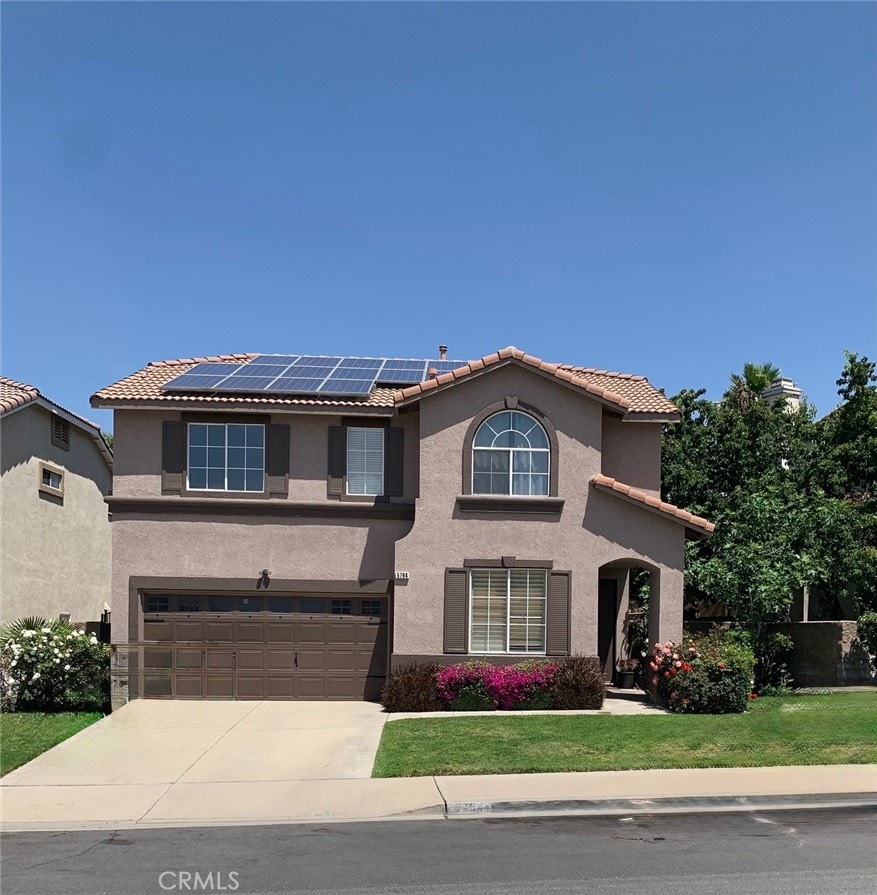 5794 Bay Hill Ln, Fontana, CA 92336 - view of front facade featuring a tile roof, stucco siding, roof mounted solar panels, and driveway