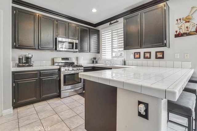 5794 Bay Hill Ln, Fontana, CA 92336 - kitchen with appliances with stainless steel finishes, a peninsula, tile countertops, light tile patterned floors, and recessed lighting