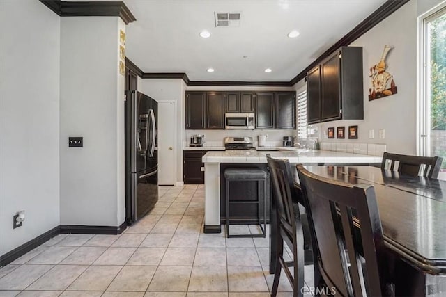 5794 Bay Hill Ln, Fontana, CA 92336 - kitchen with stainless steel appliances, tile countertops, crown molding, a peninsula, and light tile patterned floors