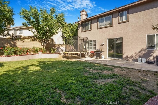 5794 Bay Hill Ln, Fontana, CA 92336 - back of house featuring a trampoline, stucco siding, a patio area, and a chimney