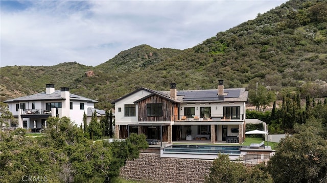 2775 Calbourne Ln, Westlake Village, CA 91361 - back of house with solar panels, a balcony, a chimney, an outdoor pool, and a mountain view