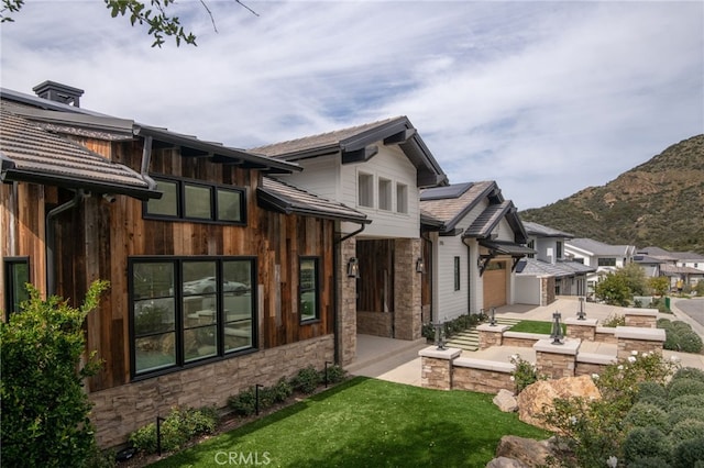 2775 Calbourne Ln, Westlake Village, CA 91361 - back of house featuring stone siding, solar panels, a mountain view, and a yard