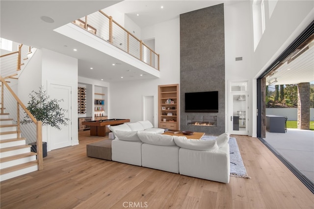 2775 Calbourne Ln, Westlake Village, CA 91361 - living room featuring a high ceiling, hardwood / wood-style floors, stairway, a fireplace, and built in features