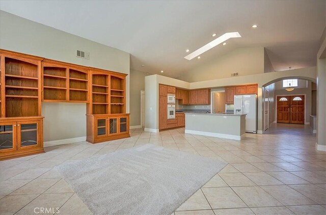 24347 Silver Bullet Way, Murrieta, CA 92562 - unfurnished living room with light tile patterned floors, arched walkways, a skylight, recessed lighting, and baseboards