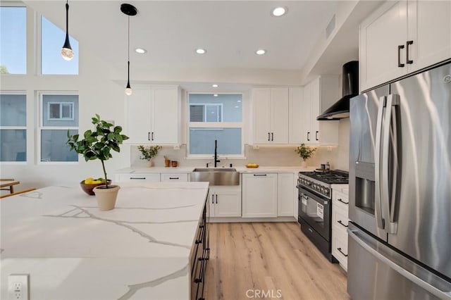 1802 Blossom Ln, Redondo Beach, CA 90278 - kitchen featuring appliances with stainless steel finishes, wall chimney range hood, white cabinetry, light wood-style flooring, and pendant lighting