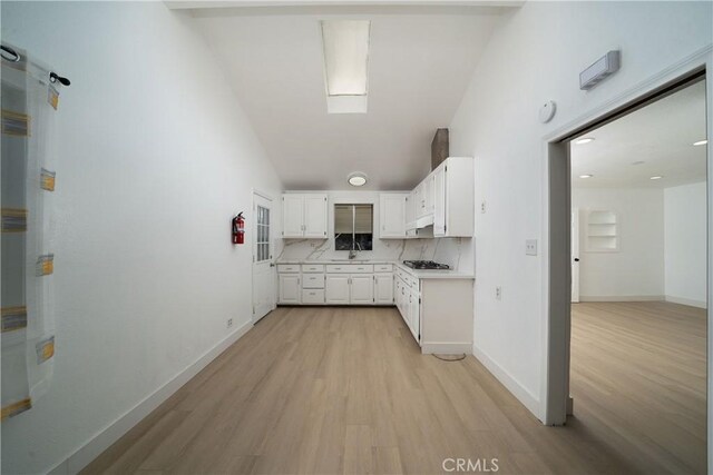 15251 Cedarwood Ave, Midway City, CA 92655 - kitchen featuring light wood finished floors, white cabinetry, light countertops, vaulted ceiling, and decorative backsplash
