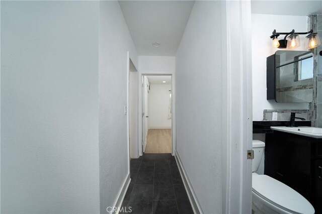 15251 Cedarwood Ave, Midway City, CA 92655 - hallway with baseboards, dark tile patterned floors, and a sink