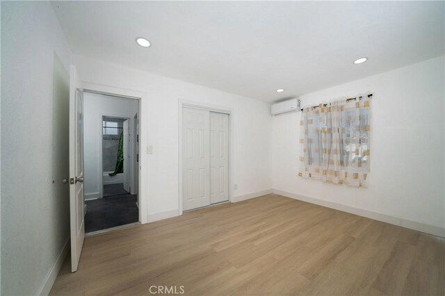 15251 Cedarwood Ave, Midway City, CA 92655 - unfurnished bedroom featuring an AC wall unit, light wood-style flooring, recessed lighting, a closet, and baseboards