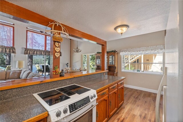 37731 Shoreline Dr, Bass Lake, CA 93604 - kitchen with range with electric cooktop, light wood-style floors, brown cabinets, baseboards, and a chandelier