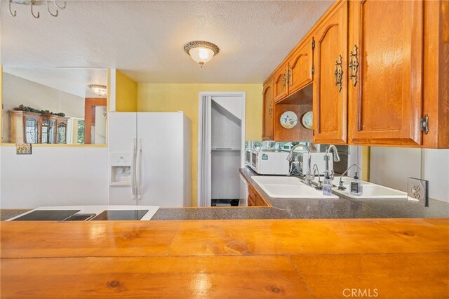 37731 Shoreline Dr, Bass Lake, CA 93604 - kitchen with white appliances, brown cabinets, a textured ceiling, a sink, and dark countertops