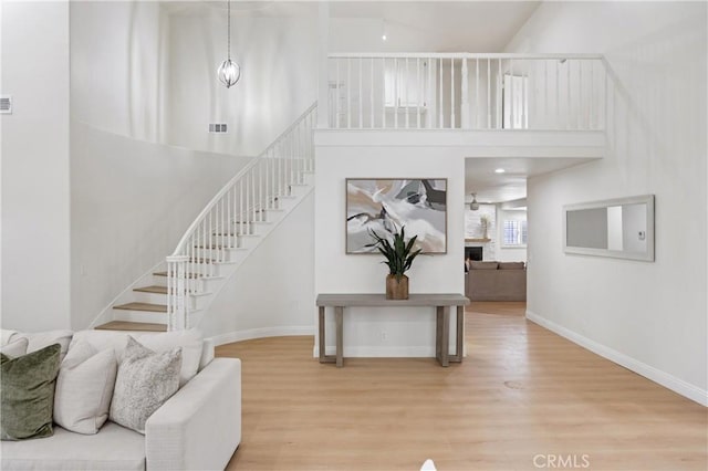 8426 Orange St, Downey, CA 90242 - staircase with wood finished floors, a high ceiling, and a fireplace