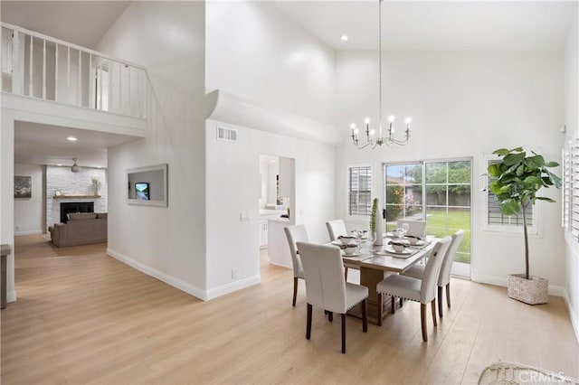8426 Orange St, Downey, CA 90242 - dining area with a towering ceiling, light wood-style flooring, a chandelier, a fireplace, and recessed lighting