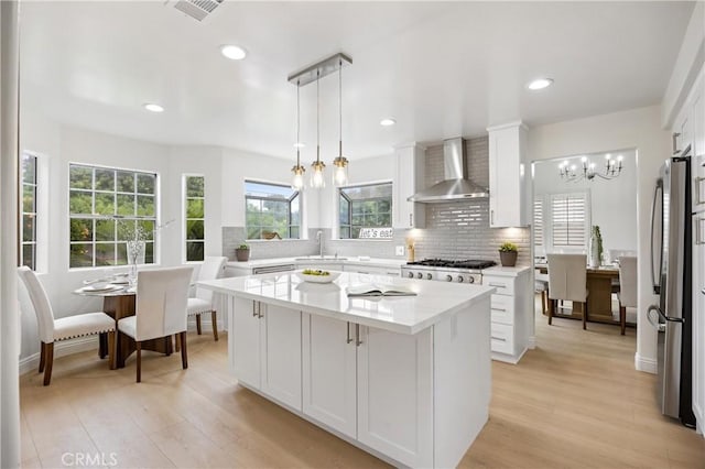 8426 Orange St, Downey, CA 90242 - kitchen with wall chimney exhaust hood, a chandelier, stainless steel appliances, decorative backsplash, and white cabinets
