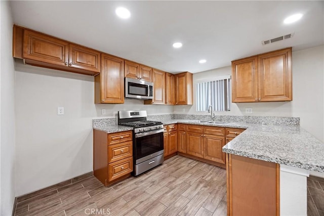 8426 Orange St, Downey, CA 90242 - kitchen featuring appliances with stainless steel finishes, a peninsula, light wood-style flooring, brown cabinetry, and recessed lighting