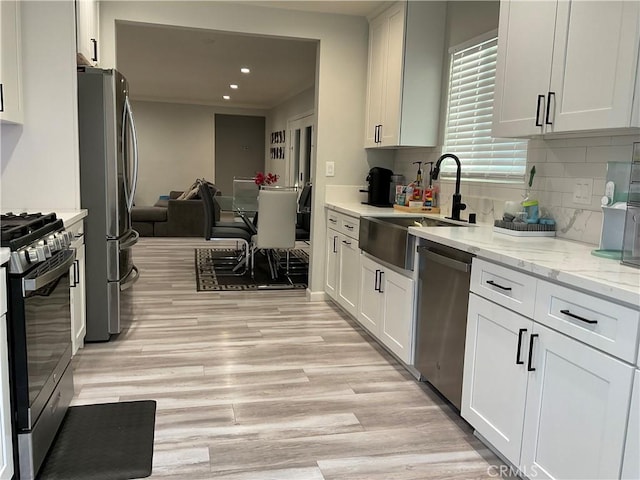 114 S Acacia Ave, Rialto, CA 92376 - kitchen with appliances with stainless steel finishes, decorative backsplash, light wood-type flooring, white cabinetry, and light stone countertops
