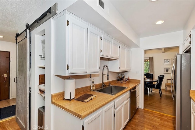 966 Willow Creek Rd Unit 36, Lake Arrowhead, CA 92352 - kitchen featuring a sink, stainless steel appliances, light wood-type flooring, white cabinets, and a textured ceiling